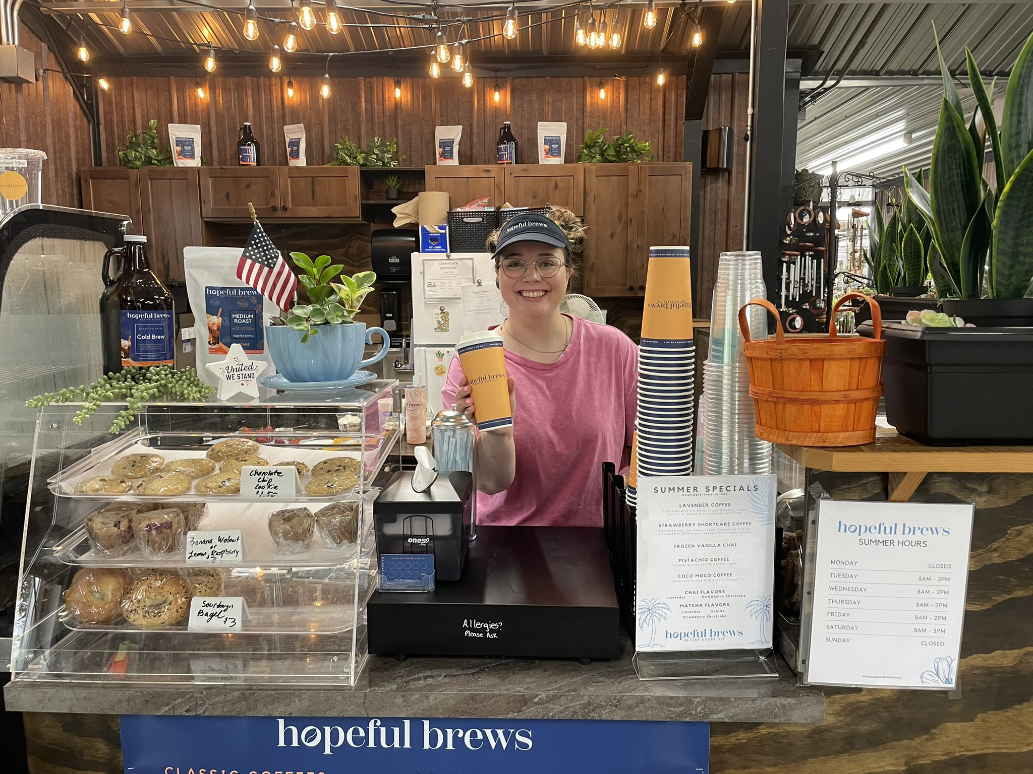 Barista at the counter holding a freshly made coffee in a cup.